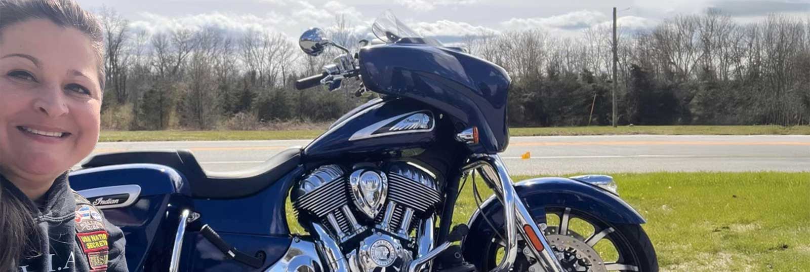 Biker woman posing in front of motorcycle