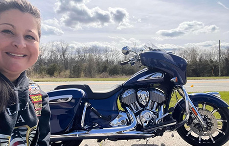 Biker woman posing in front of motorcycle