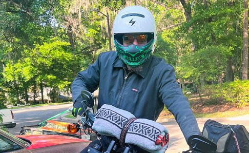 biker guy standing next to motorcycle with helmet in